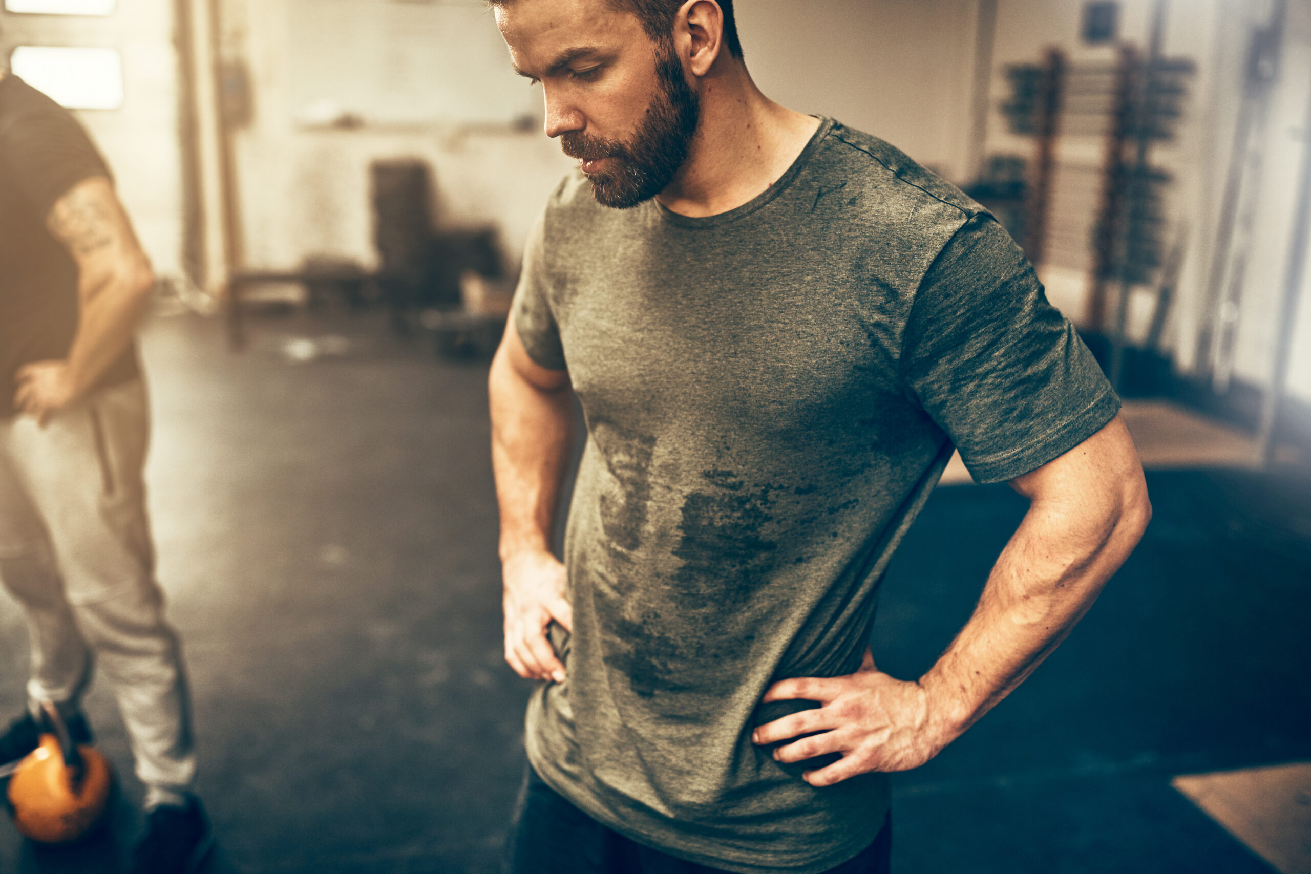 Baton Rouge Krav Maga Thunderdome Fit young man in sportswear standing with his hands on his hips in a gym sweating after a workout session